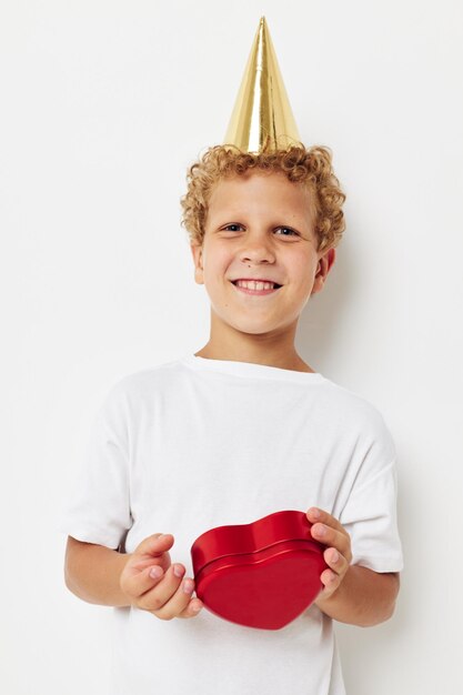 Cute boy with a cap on his head a gift box in the shape of a heart