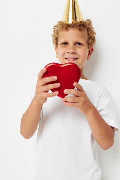 Cute boy with a cap on his head a gift box in the shape of a heart