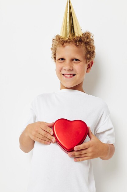 Cute boy with a cap on his head a gift box in the shape of a heart