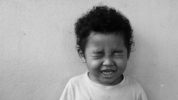 Photo cute boy with closed eyes against wall