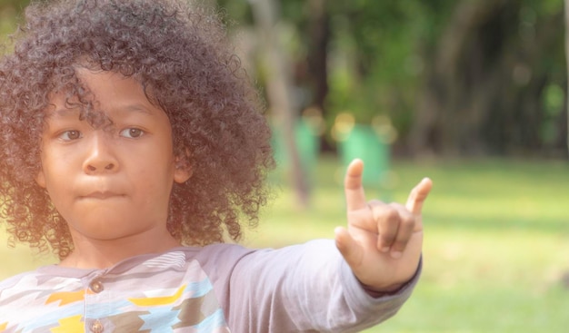 Photo cute boy with curly hair looking away while gesturing in park