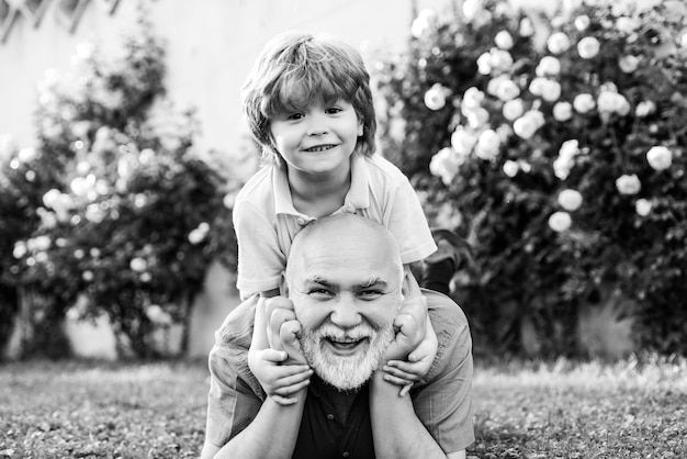 Cute boy with dad playing outdoor happy family grandson hugs his grandpa on holiday happy grandfathe...