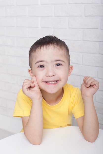 座っている眼鏡でダウン症のかわいい男の子