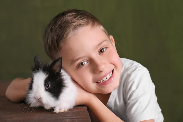 Foto ragazzo carino con coniglio divertente su sfondo colorato