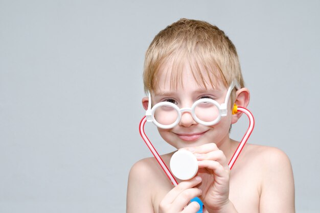 Cute boy with glasses and phonendoscope playing doctor. Portrait