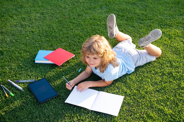 Cute boy writing on notebook outdoors summer camp kids learning and education concept