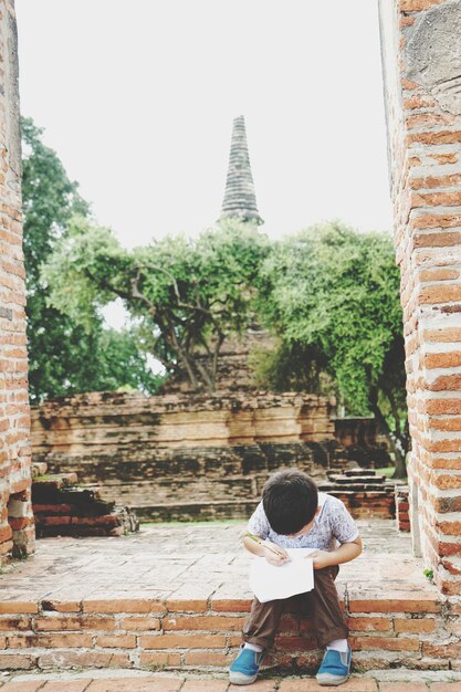 Photo cute boy writing in paper at entrance