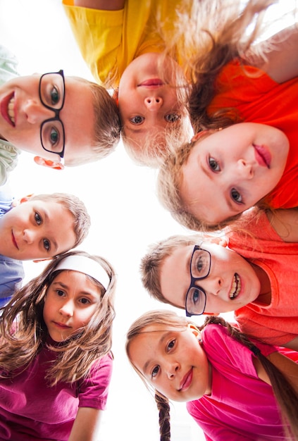 Cute boys and pretty girls looking at camera view from down Team of kids outdoors Summer camp and holidays