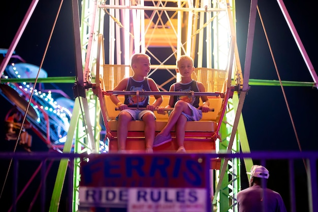 Photo cute boys sitting at amusement park ride