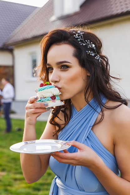 Photo cute bridesmaid eats wedding cake on the wedding ceremony