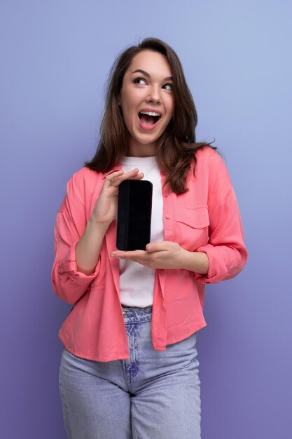 A cute brunette lady with dark hair below her shoulders in a shirt and jeans demonstrates a