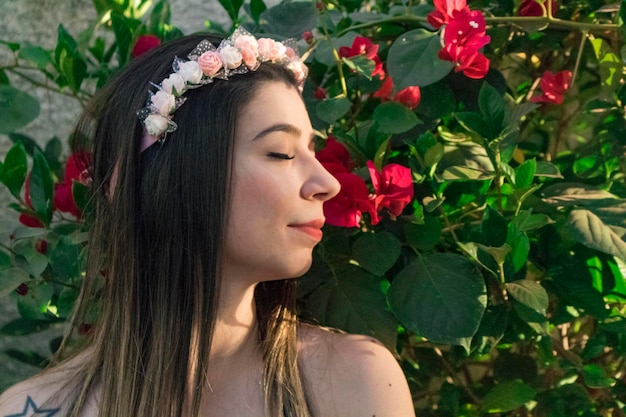 庭に花のティアラまたはヘアバンドを持つかわいいブルネットのティーンエイジャーの女の子。ヒッピーコスチュームコンセプト。