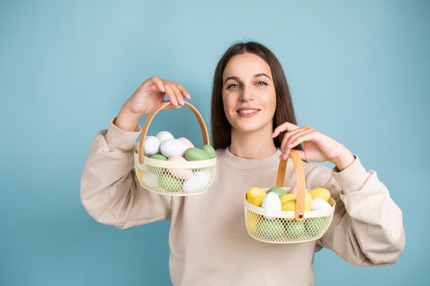 Cute brunette woman holds painted Easter eggs in baskets in her hands Easter