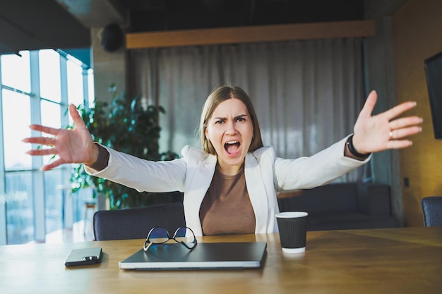 Cute business woman sitting at the desk and incredibly angry modern office