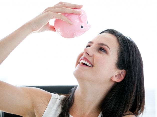 Cute businesswoman looking at a piggybank 