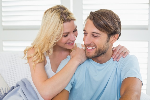 Photo cute casual couple sitting on couch under blanket