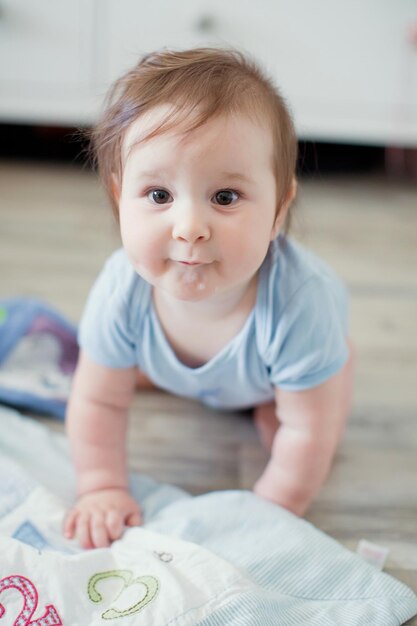 Cute caucasian baby in a blue cloth playing with toys