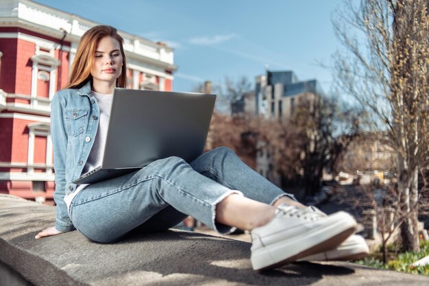 Cute caucasian longhaired woman using laptop in the city