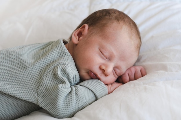 Cute caucasian several days old newborn sleeping on stomach on white blanket at homeadorablecalm inn