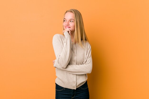 Cute caucasian teenager posing standing against a orange wall