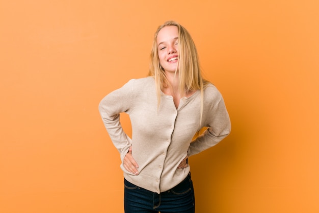 Cute caucasian teenager posing standing against a orange 