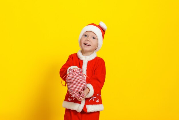 Cute caucasian threeyearold boy dressed as Santa Claus put his hand into a sack with New Years