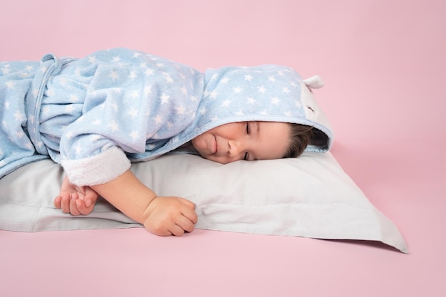 Cute caucasian toddler sleeping on his pillow over pink background Child sleep concept High quality photo