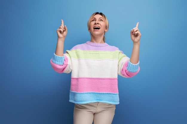 Милая очаровательная белокурая молодая женщина в полосатом свитере демонстрирует радостные эмоции счастья на