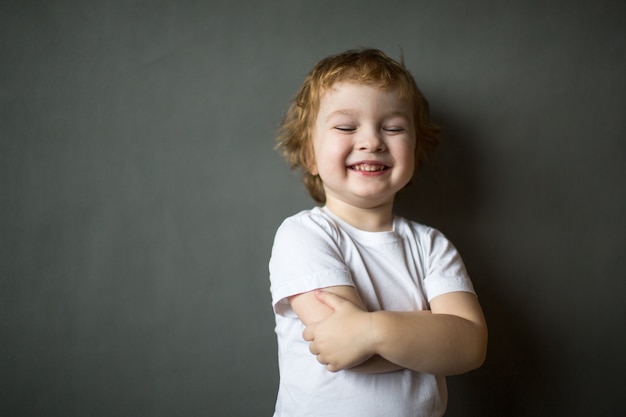 かわいい陽気な幸せな縮毛の少年が立っています。