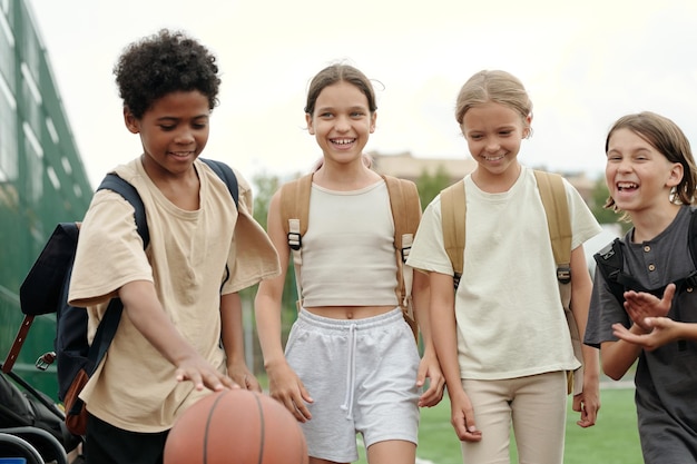 Foto simpatici amici interculturali allegri in abbigliamento sportivo che si godono una passeggiata dopo la scuola