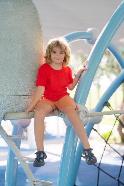 Cute child boy plays on playground kid climbing on playground