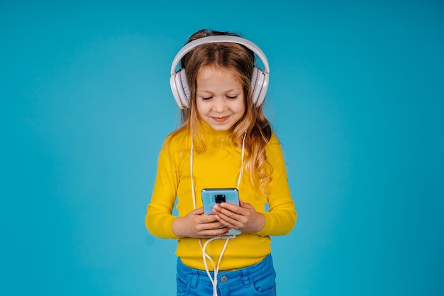 Cute child girl hold smartphone isolated on blue background