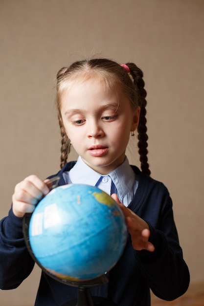 La ragazza sveglia del bambino osserva il globo