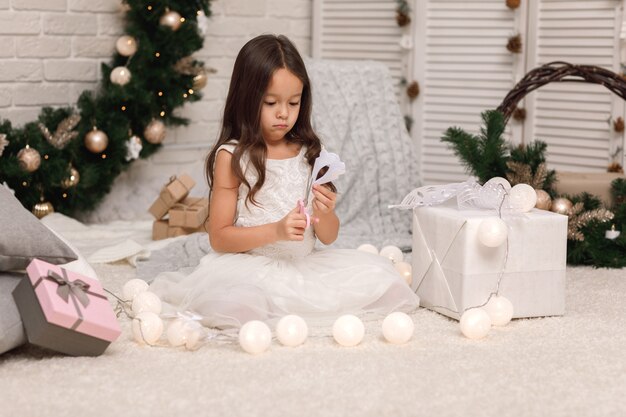 Cute child girl makes paper snowflakes for decoration Christmas tree at home