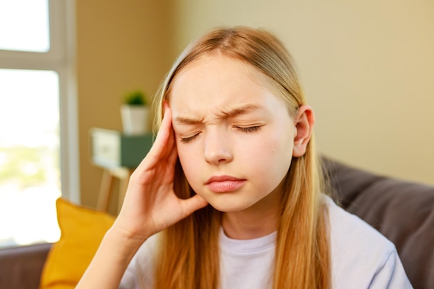 Cute child girl wearing casual clothes with hand on head for pain in head because stress in school