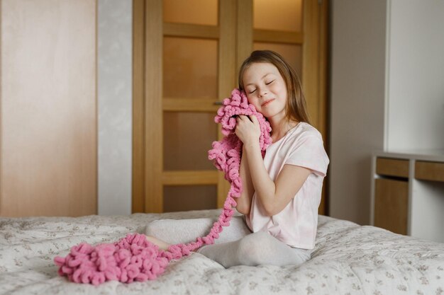 Cute child girl with needlework in the real interior of the bedroom at home