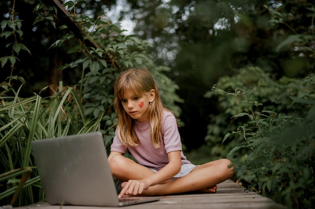 사진 귀여운 아이가 정원에서 노트북을 가지고 놀고 있습니다.