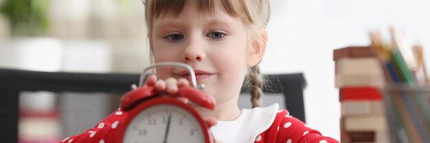 Il bambino carino impara a capire il tempo e gioca con l'orologio retrò rosso