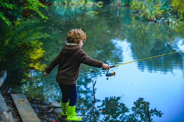 Cute child little boy pulling rod while fishing on lake.