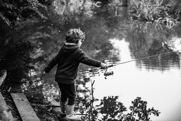 湖で釣りをしながらロッドを引っ張るかわいい子供の小さな男の子