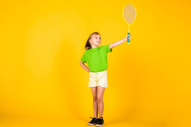 Simpatico bambino gioca a tennis o a badminton. stile di vita attivo. pieno di energia. bella ragazza teenager con la racchetta da tennis. stile di moda sportiva per bambini. forma fisica e salute. infanzia felice. lo sport è la nostra vita.