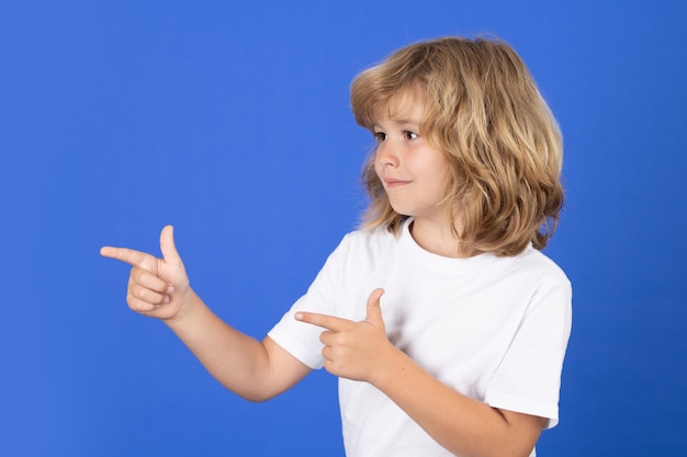 Foto bambino carino che punta il dito sullo sfondo dello studio isolato kid che punta al copyspace che mostra le offerte promozionali punta lontano concetto di prodotto promozionale pubblicitario