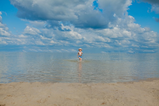 Cute child running from sea waves on beach