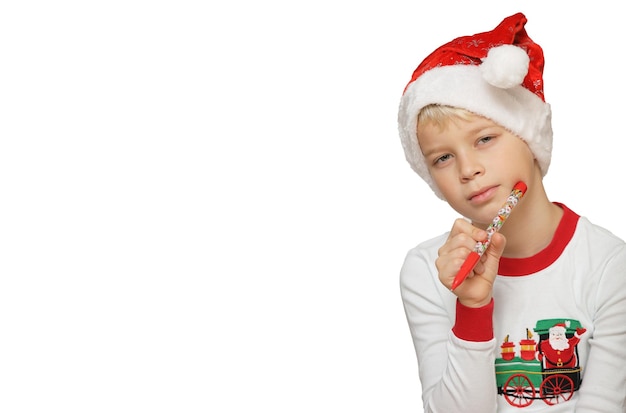 Cute child in Santa hat,  thinking about presents on white background.A boy looks straight