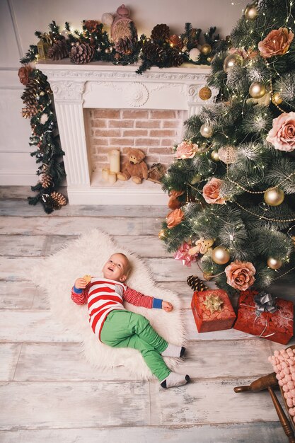 Cute child in tpajamas spend time with family at home interior on background of the Christmas tree