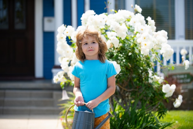 Cute child waters plants in backyard garden with watering can