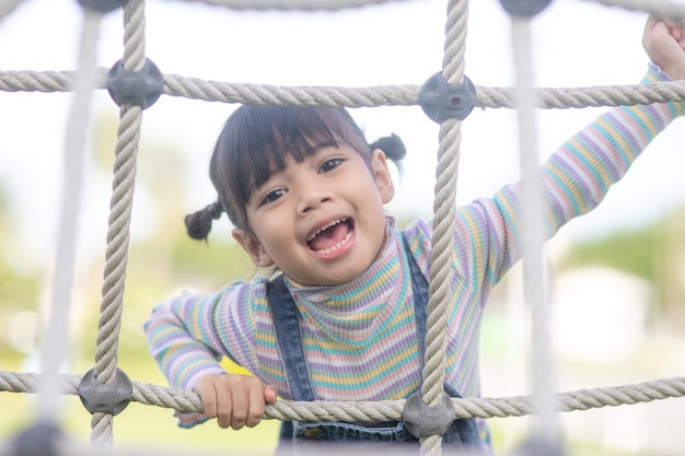 かわいい子供たち。アドベンチャーパークのロープ遊び場構造に登るアジアの女の子