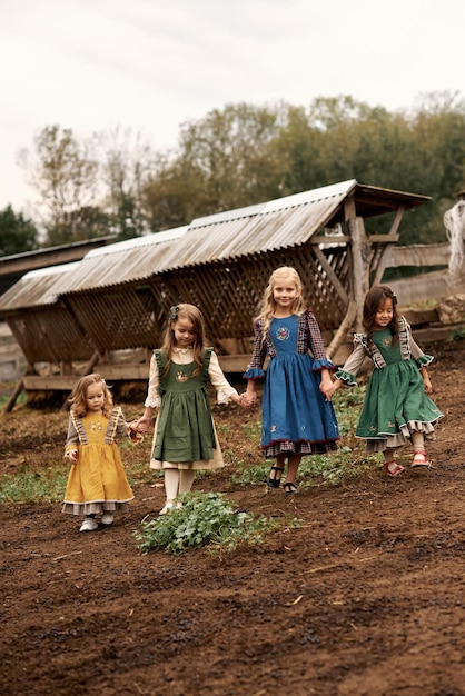 Милые дети в красивых зеленых платьях гуляют по ферме на фоне коз