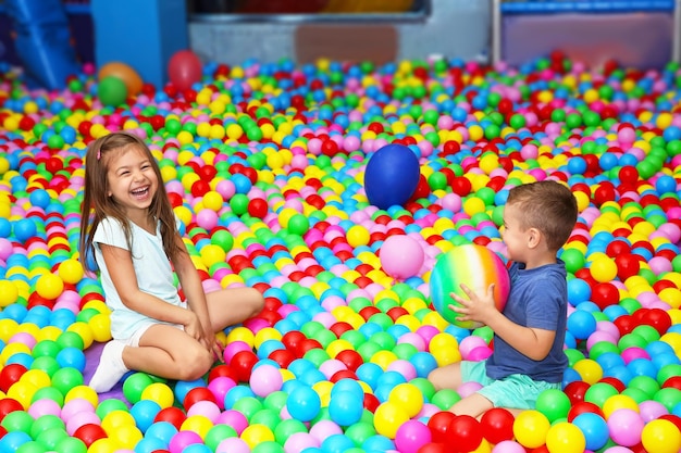 Cute children playing among plastic balls