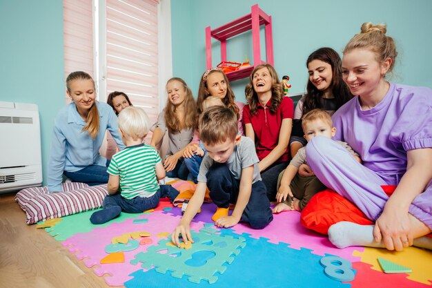 Cute children playing with soft puzzles sitting on a floor